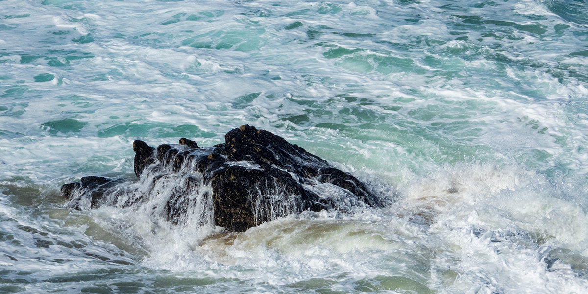 The sea foaming around a rock at Bedruthan, Cornwall.